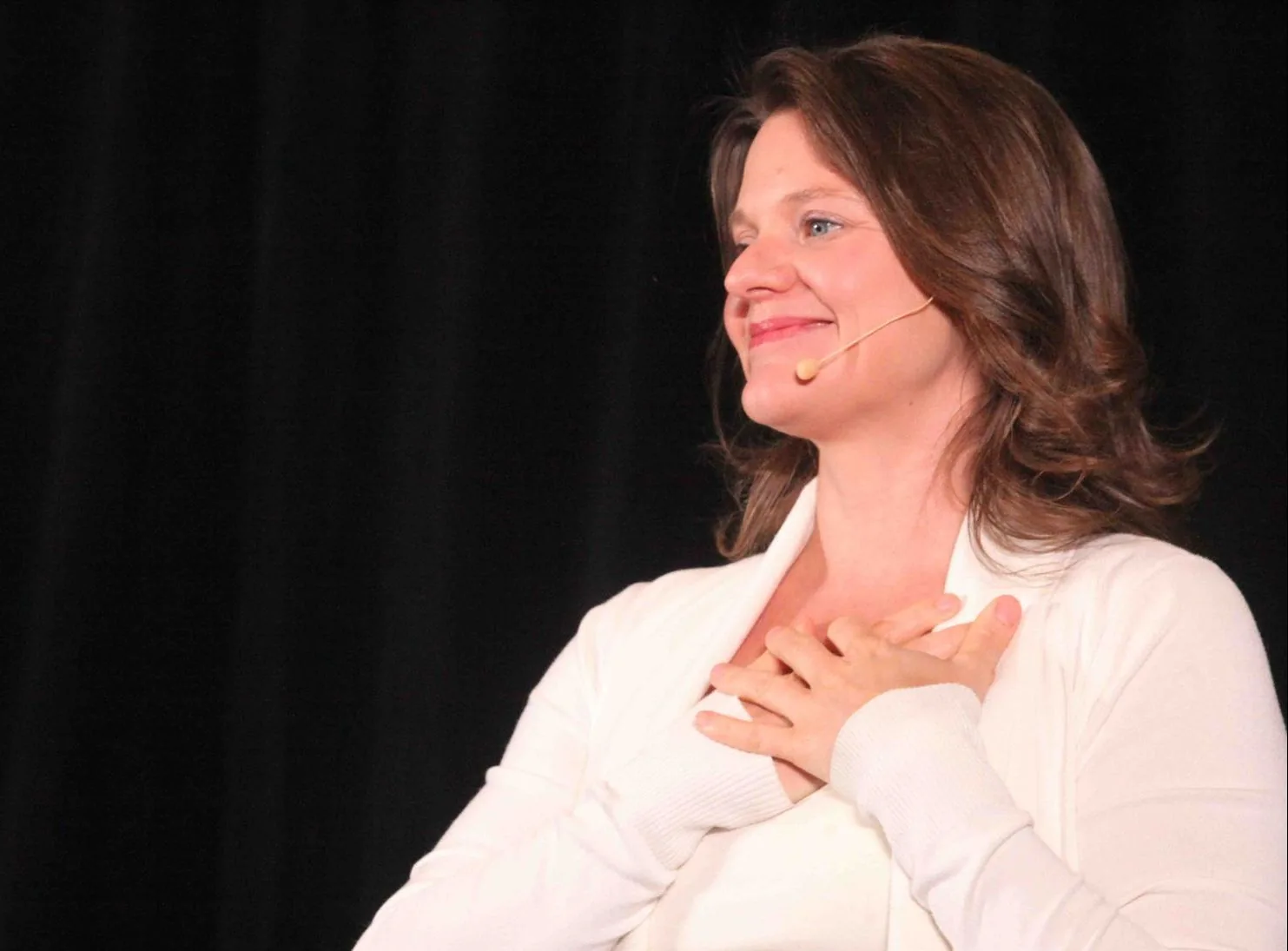 Callan Rush on stage, smiling with her hands on her heart