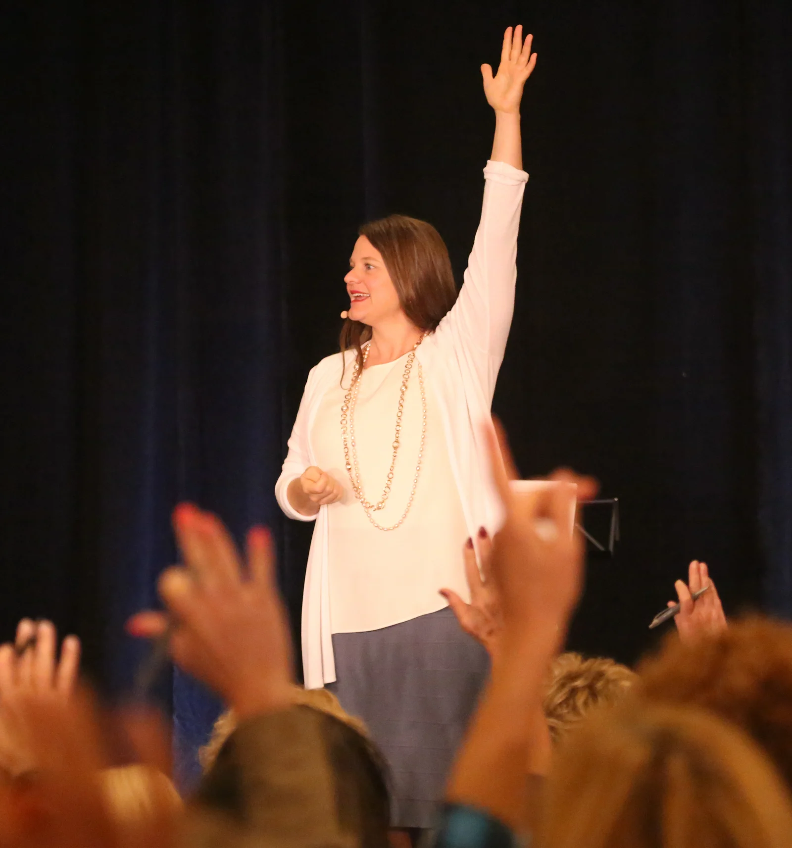 Callan Rush on stage with one arm raised as the audience raises their hands